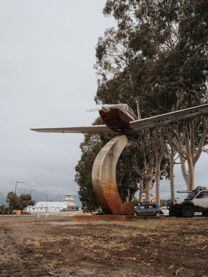 Weathered aircraft named Sugar Bird Lady beside trees under an overcast sky